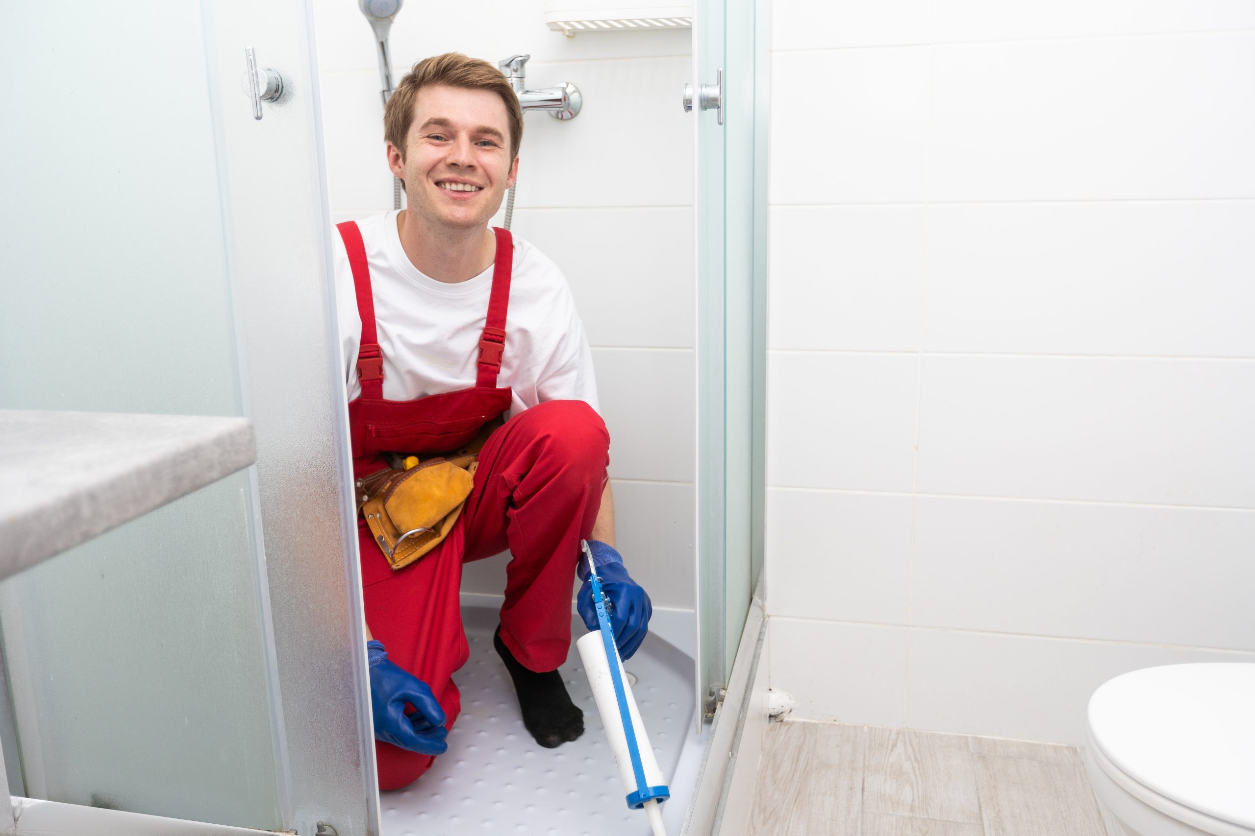 plumber using silicone cartridge for fixing aluminum batten of shower cabin